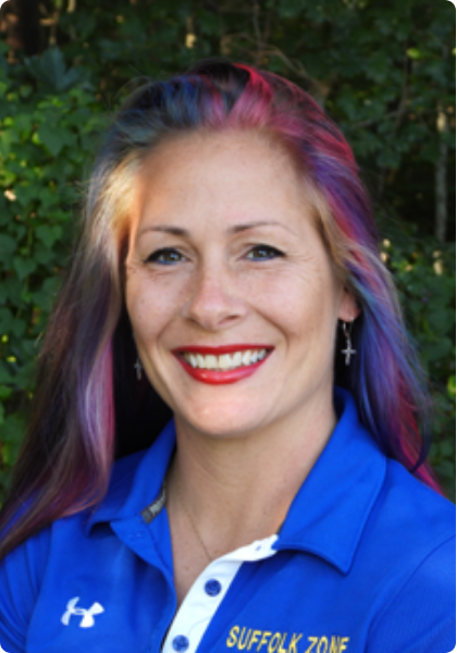 Woman smiling in a blue Suffolk Zone polo shirt with purple-streaked hair outdoors