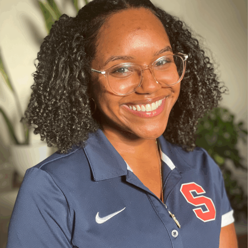 Smiling person wearing glasses and a blue Syracuse polo shirt against a light background