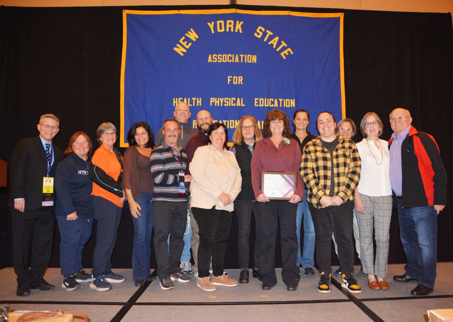 Group of people standing onstage in front of a New York State Health Panel Education banner