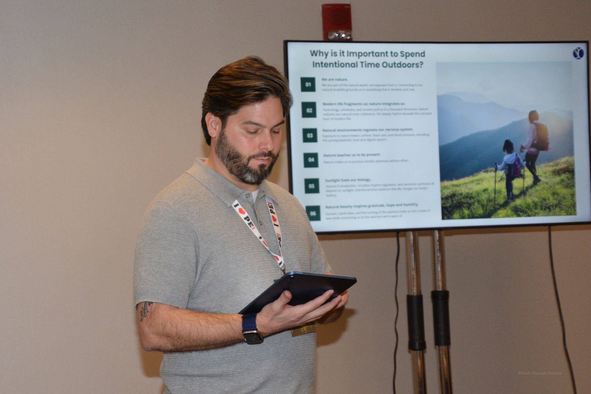 Man presenting beside a slide about sustainability while holding a tablet