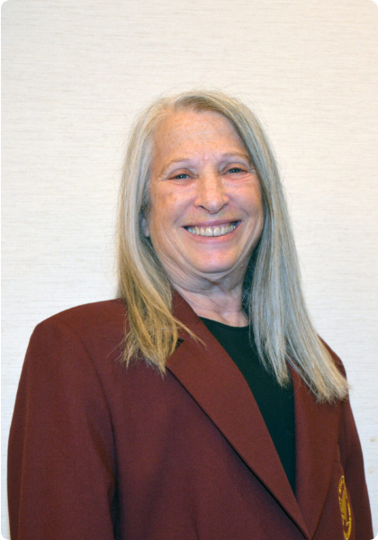 Smiling woman in a maroon blazer against a plain light background