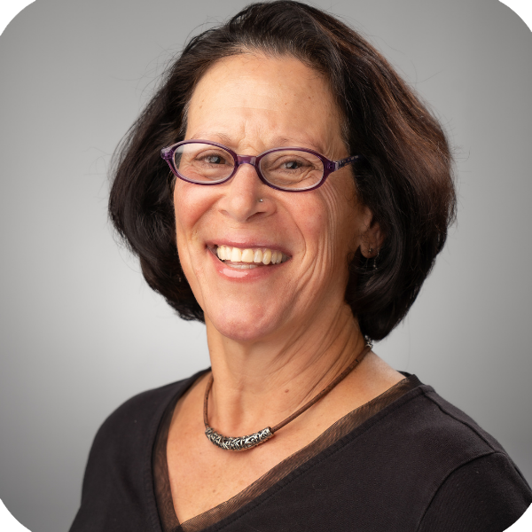 Smiling woman in a black collared shirt against a light gray backdrop