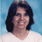 Smiling woman with dark hair in a white shirt against a blue background