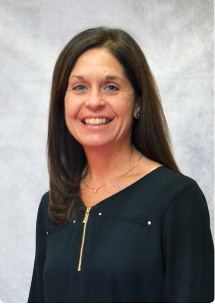 Portrait of a smiling woman in a black top against a gray studio backdrop
