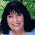 Smiling woman with dark hair against a green, leafy background