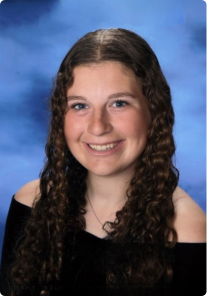 Smiling portrait of a person with curly hair in a black top against a blue studio backdrop