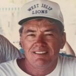 Smiling man in a white West Islip Lions cap, close-up portrait.