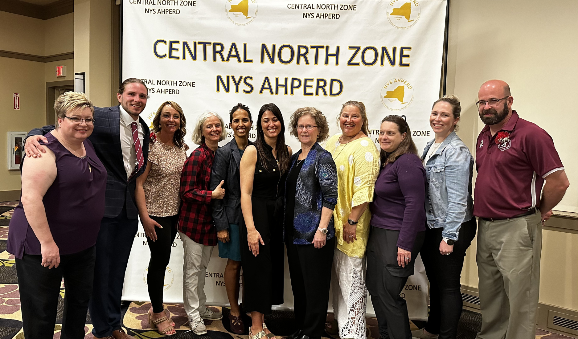 Group of people posing in front of a banner reading “Central North Zone NYS AHPERD”
