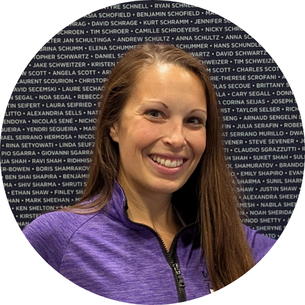 Smiling woman in a purple zip-up shirt against a dark name-filled backdrop