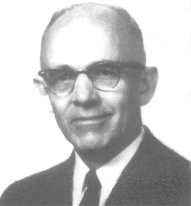 Black-and-white portrait of a man in a suit, tie, and glasses, facing forward with a slight smile