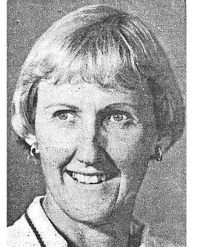 Black-and-white portrait of a smiling person with short light hair, facing the camera.