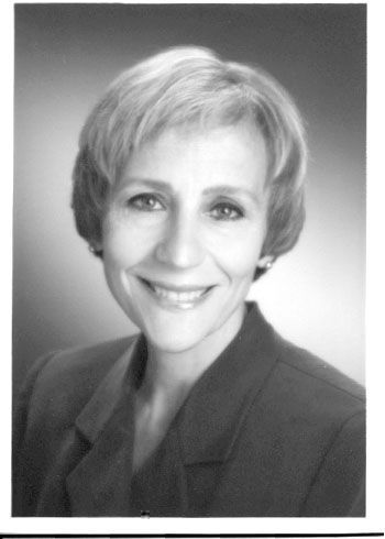 Black-and-white headshot of a smiling woman in a blazer against a plain background