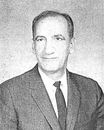 Black-and-white portrait of a man in a suit and tie, facing slightly to the side.