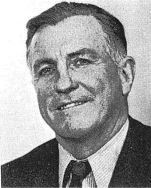Black-and-white portrait of a smiling man in a suit and tie