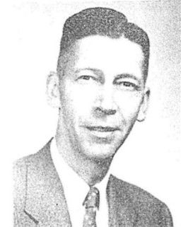 Black-and-white portrait of a man in a suit and tie, facing forward with a slight smile.