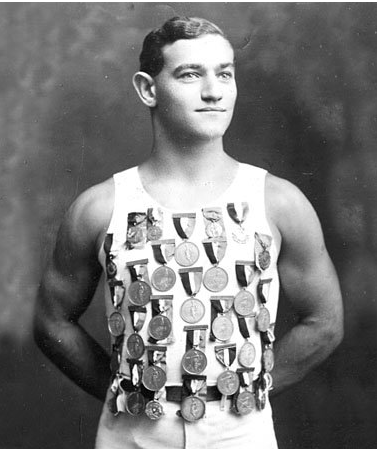 Athlete wearing a medal-covered tank top, posing in a studio portrait.