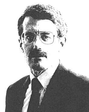 Black-and-white portrait of a man wearing glasses, a suit, and a tie.
