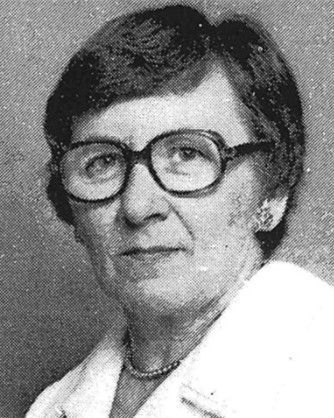 Black-and-white portrait of a person wearing glasses and a light jacket, facing the camera with a neutral expression