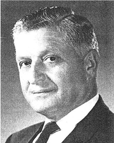 Black-and-white portrait of a man in a suit, facing slightly left with a neutral expression.
