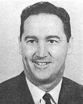 Black-and-white portrait of a smiling man in a suit and tie.