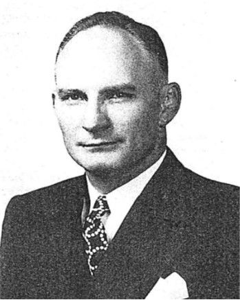 Black-and-white portrait of a man in a suit and tie, facing forward.