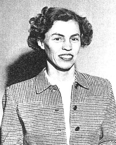 Black-and-white portrait of a smiling person in a patterned jacket against a plain background