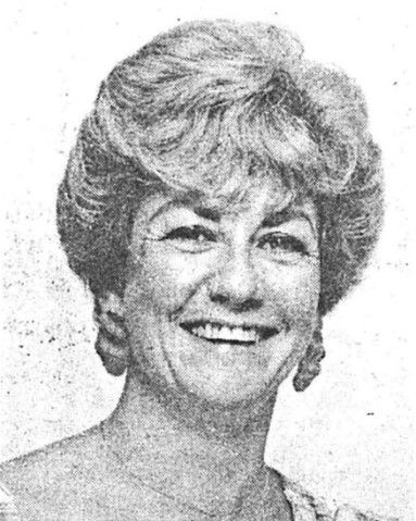 Black-and-white portrait of a smiling person with short, voluminous hair.