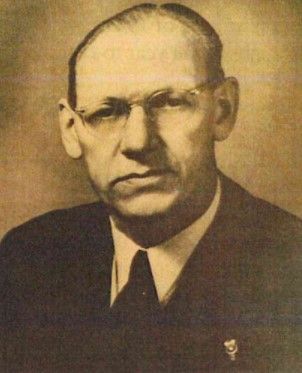 Sepia portrait of a man in a suit and tie, wearing glasses, facing forward with a serious expression