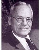 Portrait of a man in a suit and glasses, facing the camera with a slight smile.