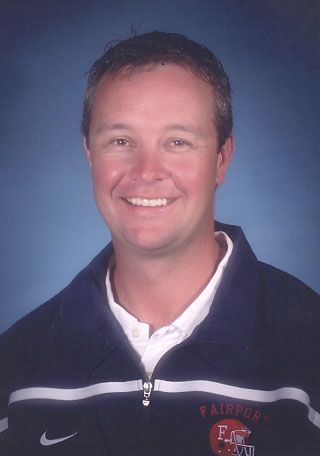 Smiling man in a navy pullover jacket against a blue studio background