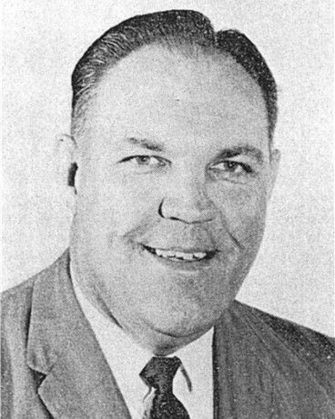 Black-and-white portrait of a smiling man in a suit and tie.