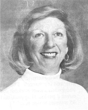 Black-and-white portrait of a smiling person in a light turtleneck sweater.