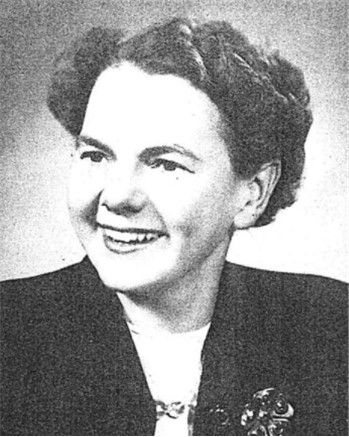 Black-and-white portrait of a smiling woman in a dark jacket and light blouse