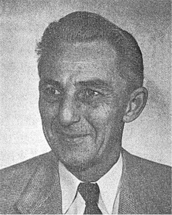 Black-and-white portrait of a man in a suit and tie, looking slightly to the side.