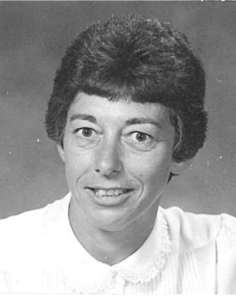 Black-and-white portrait of a person smiling, wearing a light blouse against a plain background