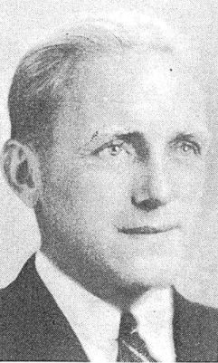 Black-and-white portrait of a man in a suit and tie, facing slightly to the right.