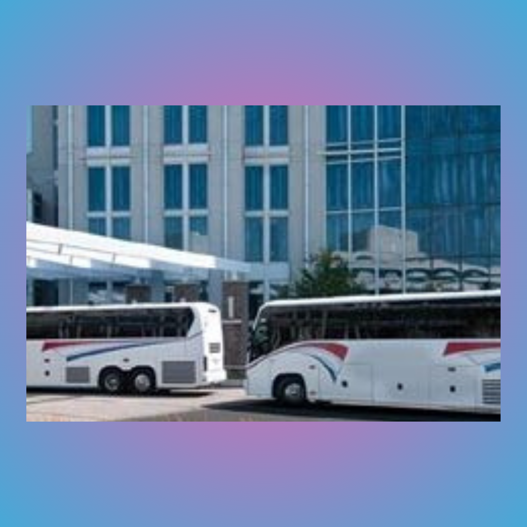 Two white tour buses parked outside a modern glass building