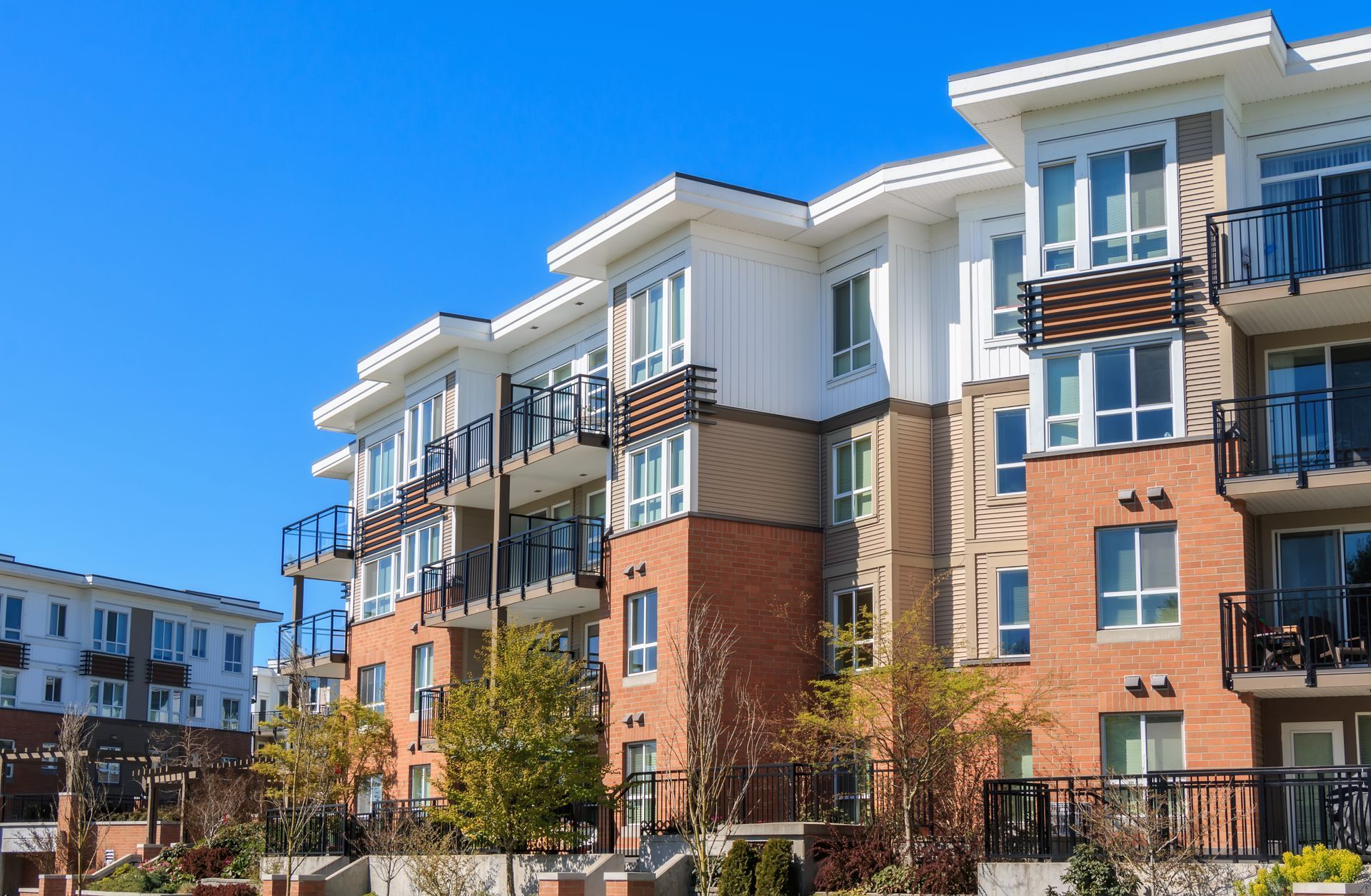Modern apartment buildings with brick and white facades under a clear blue sky