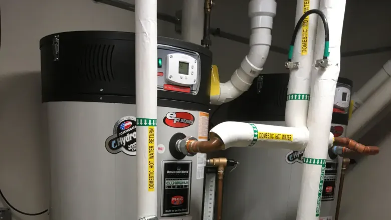 Water heater and plumbing pipes with valves in a utility closet.