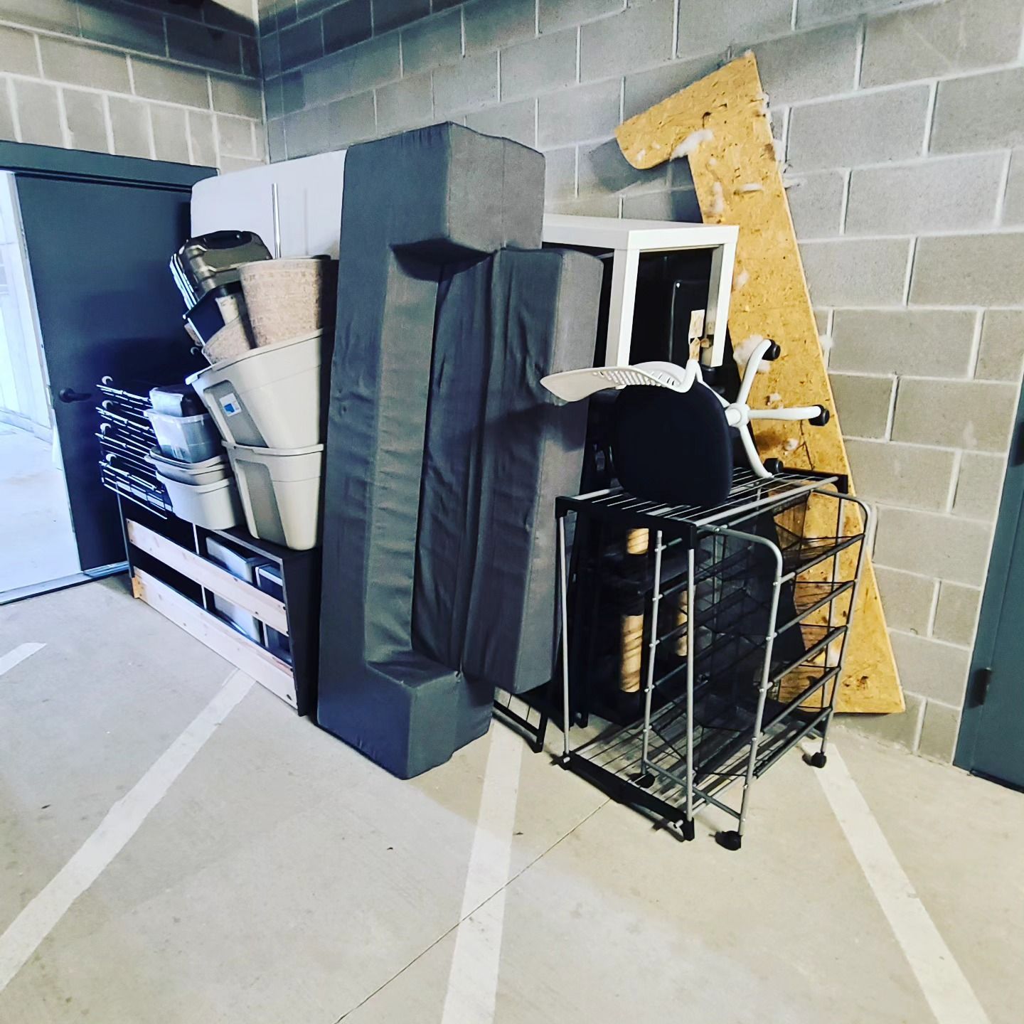 A bunch of furniture is stacked on top of each other in a garage.