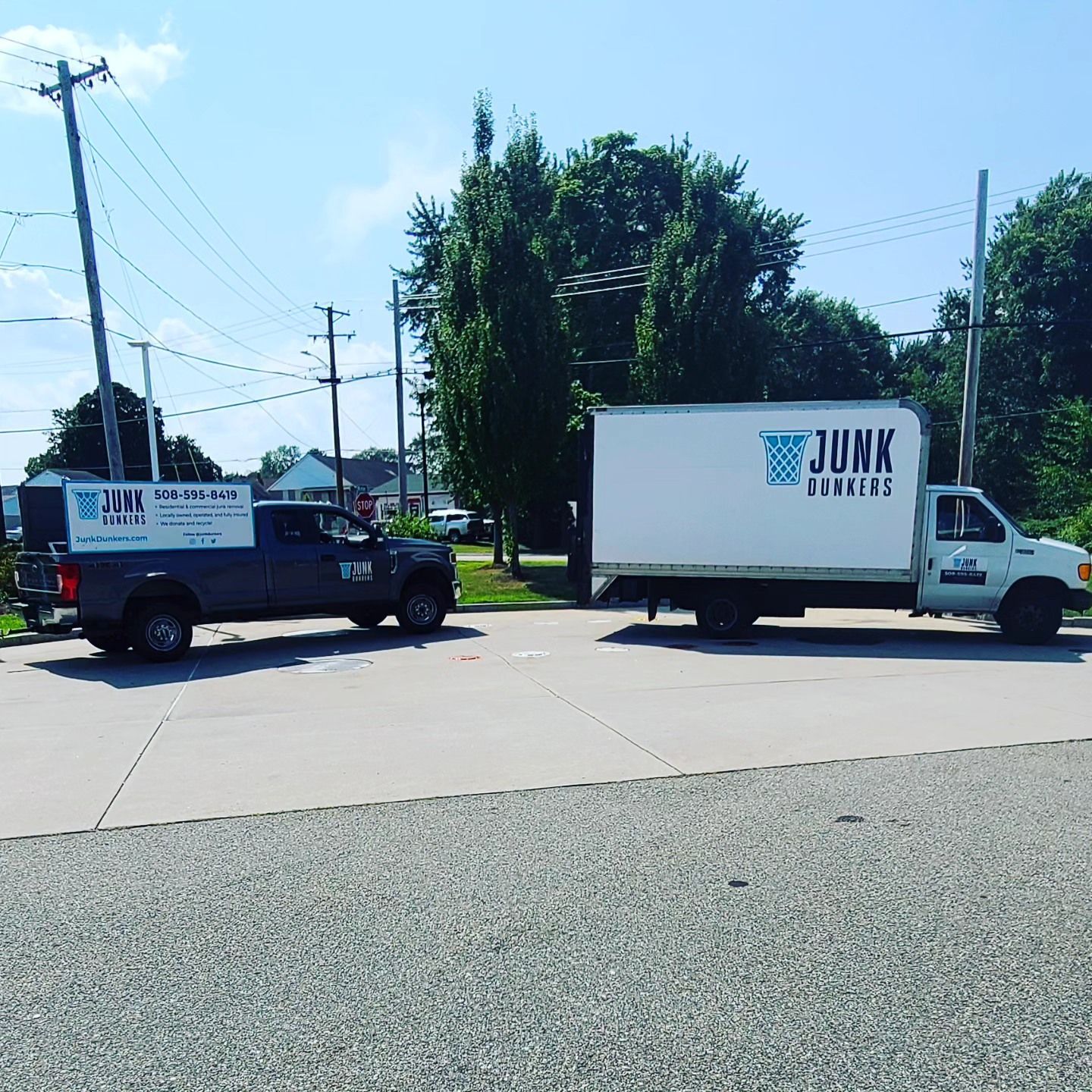 Two junk removal trucks are parked on the side of the road