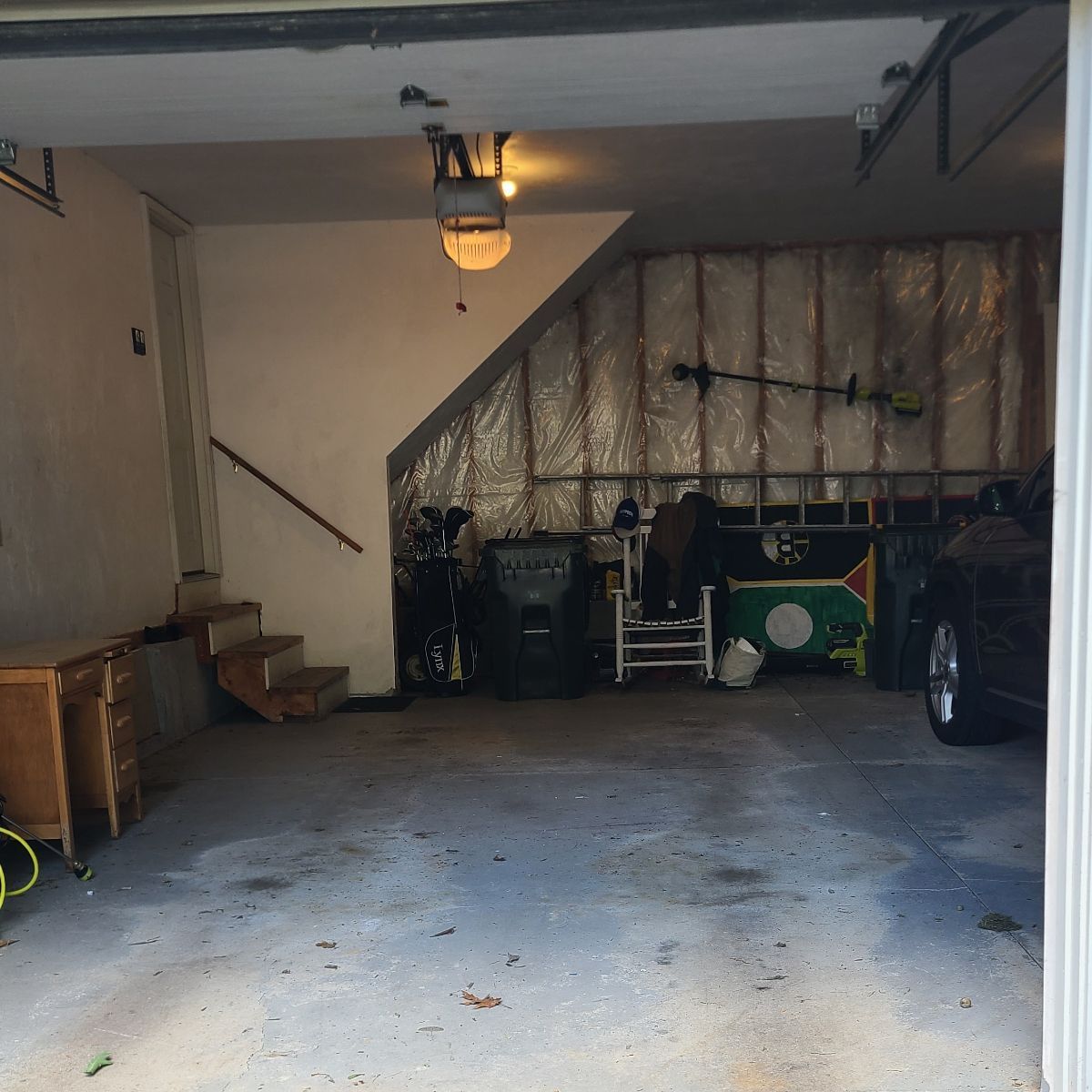 A car is parked in a garage under stairs