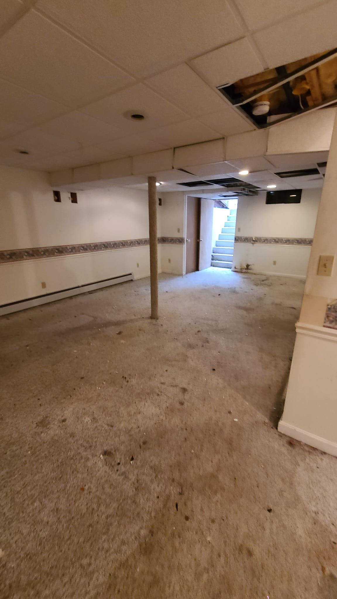 An empty basement with a staircase leading up to the second floor.