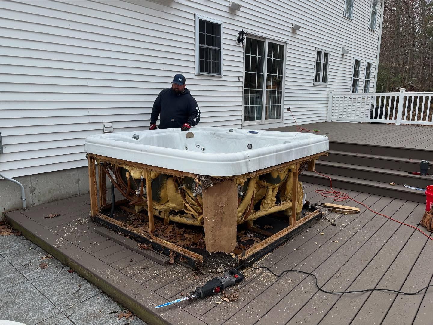 A man is standing next to a hot tub on a deck.
