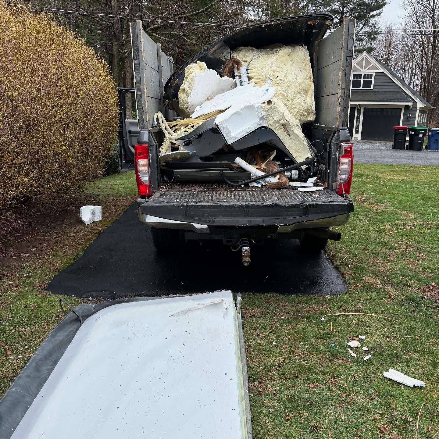 A truck filled with junk is parked in a driveway.