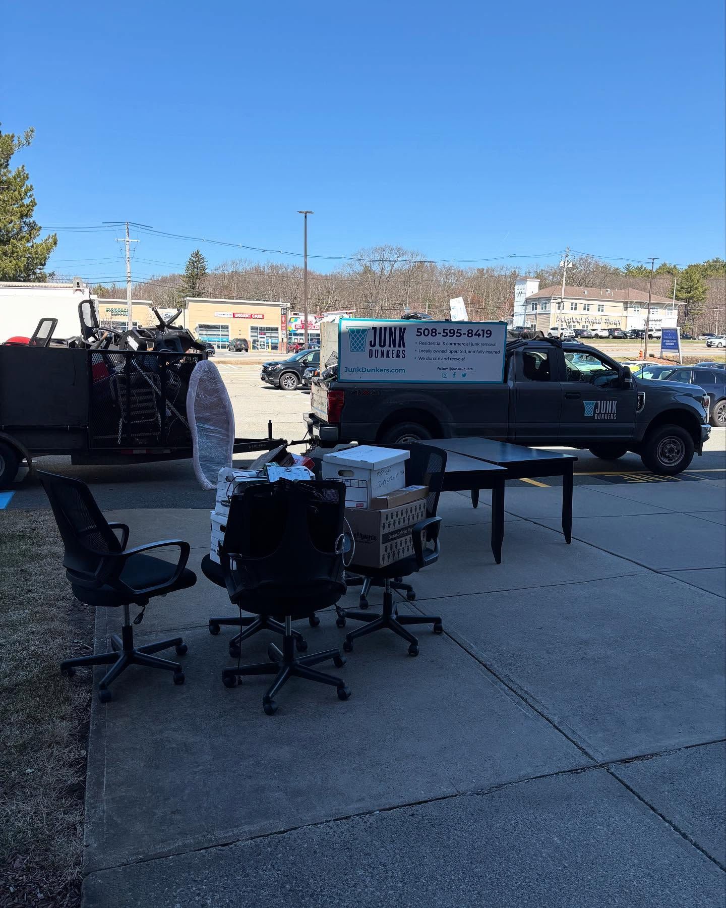 A truck is parked on the side of the road next to a table and chairs.