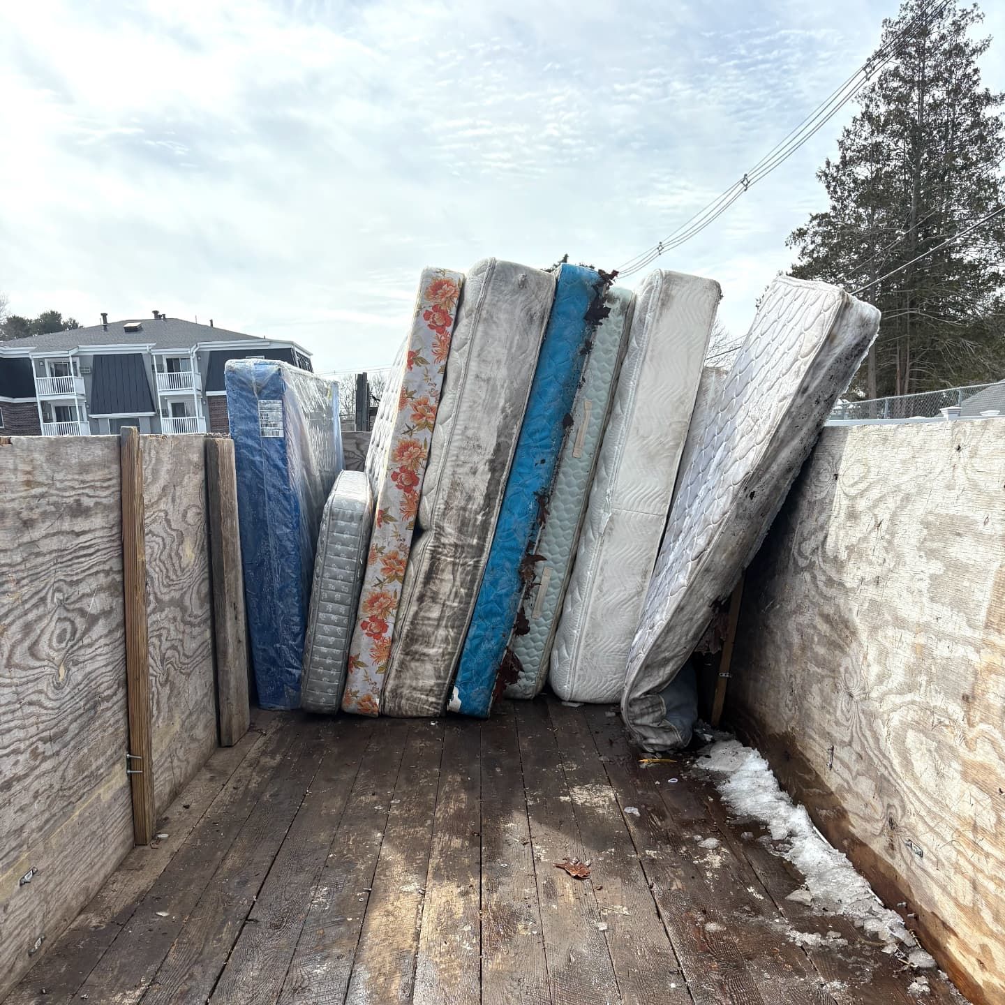 A bunch of mattresses are stacked on top of each other on the back of a truck.