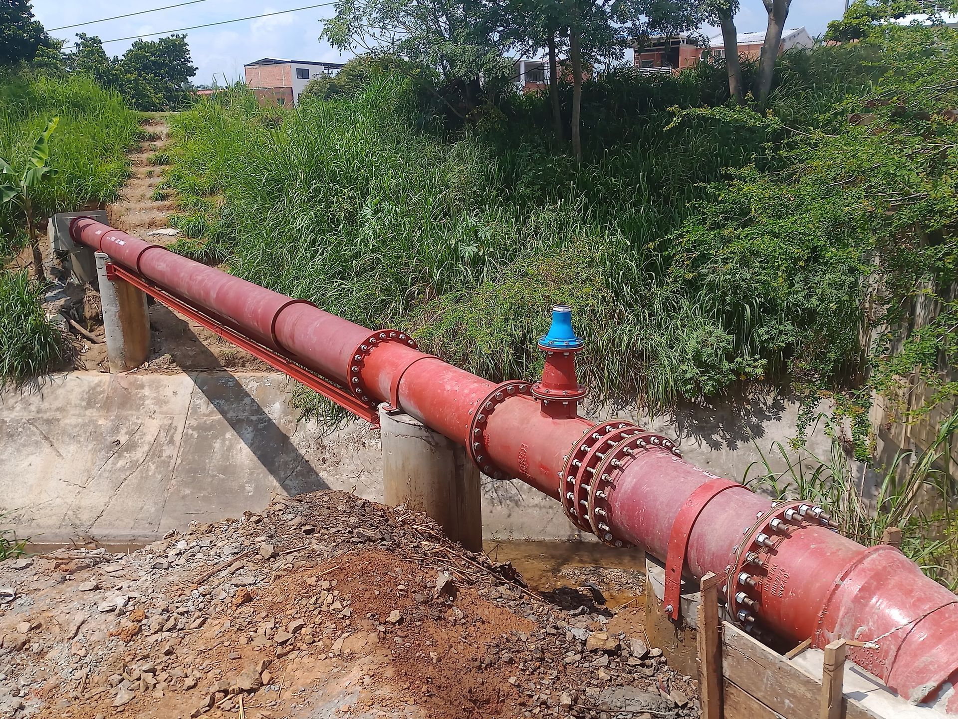 Una tubería roja con una válvula azul pasa por un campo.
