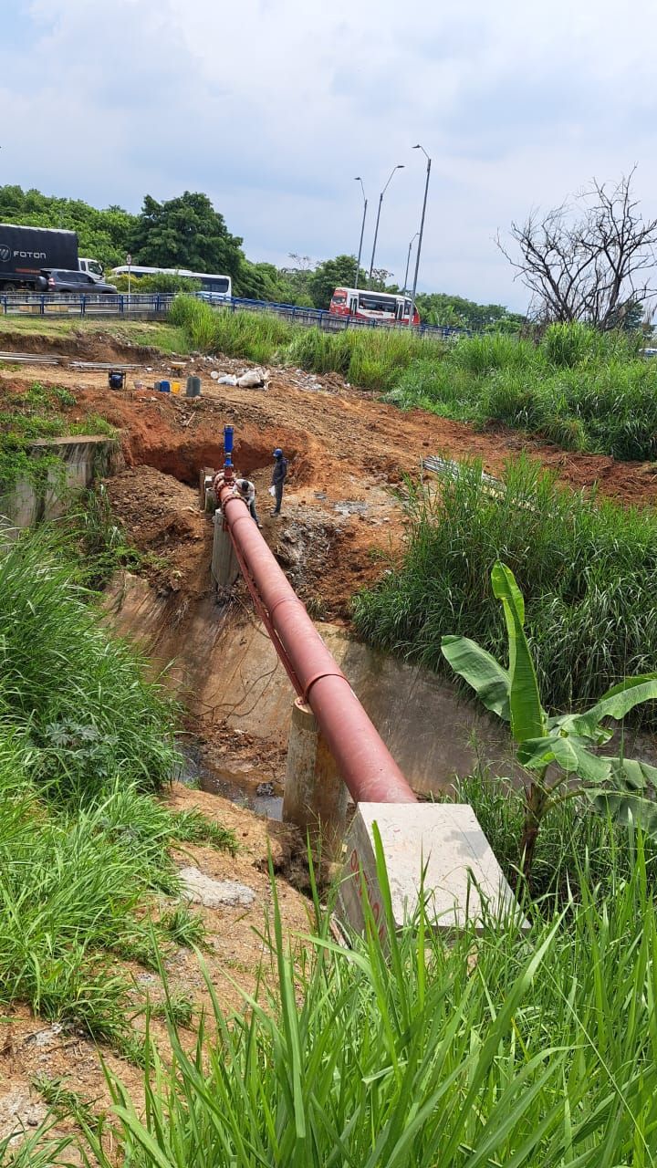 Se está instalando una tubería roja en un campo al lado de un río.