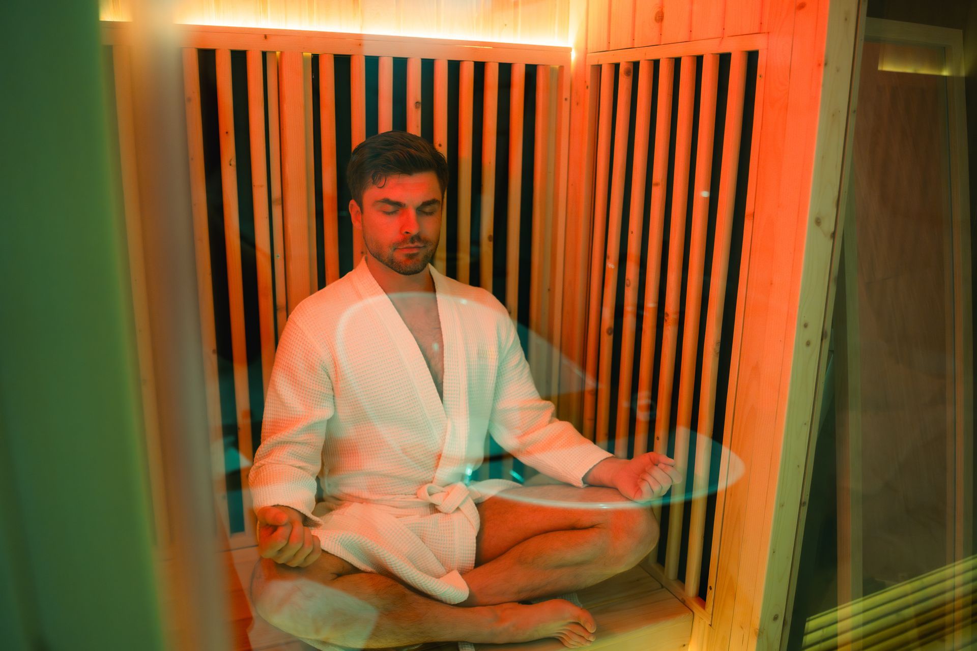Three wooden lounge chairs in a tiled indoor spa room with a stone wall and warm lighting